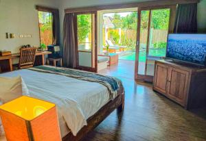 a bedroom with a bed and a flat screen tv at Dolce Magia in Gili Trawangan