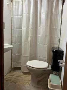 a bathroom with a toilet and a white shower curtain at 0 es 3 Dos in Treinta y Tres