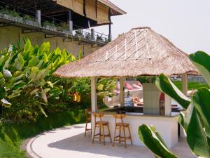 um bar ao ar livre com cadeiras e um guarda-sol de palha em Sepeda Hostel em Canggu
