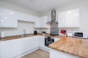 a kitchen with white cabinets and a wooden counter top at Luxury Apartments 2 Bedrooms Central Maidenhead in Maidenhead
