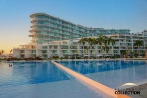 a large hotel with a swimming pool in front of a building at Nuevo Estudio en Aria Ocean 609 in Nuevo Vallarta