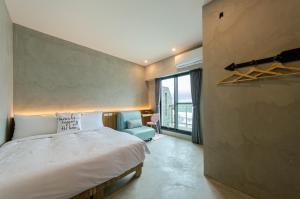 - une chambre avec un grand lit et une chaise bleue dans l'établissement 泥house, à Luodong