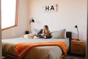a woman sitting on a bed reading a book at Josh Schweitzer's Monument House Joshua Tree in Joshua Tree