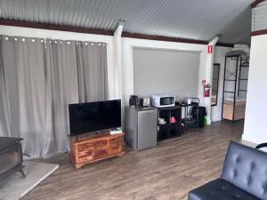 ein Wohnzimmer mit einem Flachbild-TV auf einem Holztisch in der Unterkunft Wallaby Lodges in Pokolbin