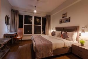 ein Hotelzimmer mit einem Bett, einem Schreibtisch und einem Fenster in der Unterkunft Carnival De Goa in Nerul