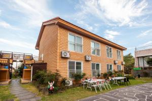 a house with a table and chairs in front of it at Red Clay Pension in Jeju