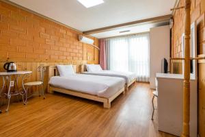 a room with two beds and a table in it at Red Clay Pension in Jeju