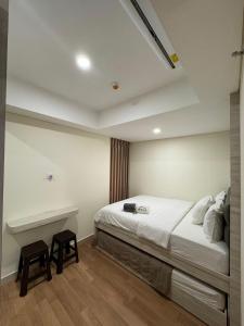 a bedroom with a bed and two stools at Pollux High Rise Apartments at Batam Center with Netflix by MESA in Batam Center
