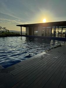 a building with a swimming pool with the sun setting at Pollux High Rise Apartments at Batam Center with Netflix by MESA in Batam Center