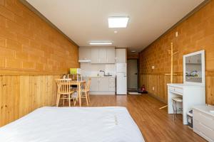 a bedroom with a bed and a kitchen with a table at Red Clay Pension in Jeju