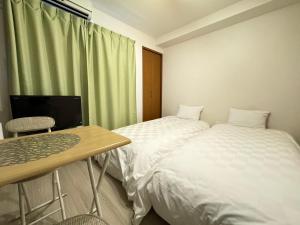 Habitación con 2 camas, escritorio y TV. en マルチステイ大阪京橋21 en Osaka