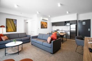 a living room with two couches and a kitchen at Quest Mackay on Gordon in Mackay