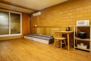 a room with a bed and a table and a microwave at Red Clay Pension in Jeju +25 photos