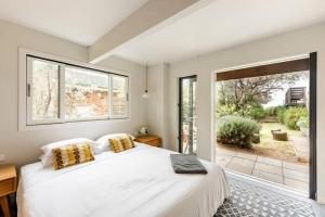 a bedroom with a large bed and a large window at One Hundred Banksias in Culburra Beach