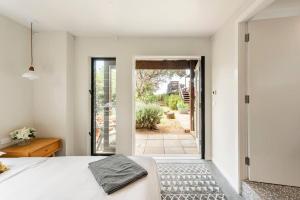1 dormitorio con 1 cama y puerta a un patio en One Hundred Banksias, en Culburra Beach