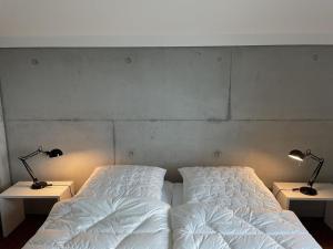 een slaapkamer met 2 bedden en 2 lampen op tafels bij Modernes Architektenhaus direkt am Golfplatz Schloss Ranzow. in Lohme