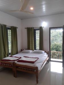 a bedroom with a bed in a room with windows at Oasis villa in Vagamon