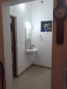 a bathroom with a sink and a clock on the wall at Oasis villa in Vagamon