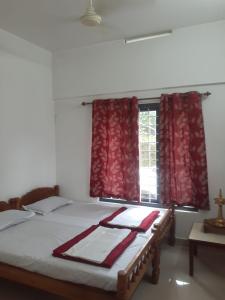 a bedroom with a bed with red curtains and a window at Oasis villa in Vagamon +8 photos