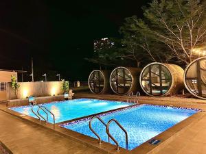 a swimming pool at night with two wine barrels at Reserve The Cozytainer in Taiping