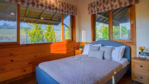 a bedroom with a bed with pillows and windows at Hill Farm Stay in Pālampur