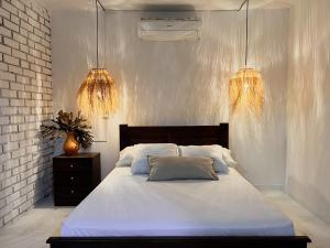 a bedroom with a white bed and two chandeliers at Casa Maria campestre con piscina in Santa Marta