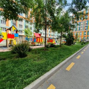 um parque com um parque infantil ao lado de uma rua em Apartament Almaty Akvarel em Almaty