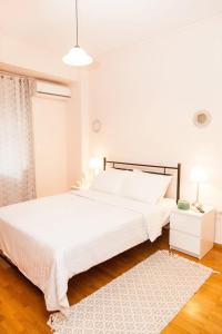 a white bedroom with a large bed and a rug at Anastasia apts Athina in Athens