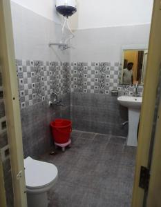 La salle de bains est pourvue de toilettes, d'un lavabo et d'un seau rouge. dans l'établissement Akash home stay, à Mussoorie