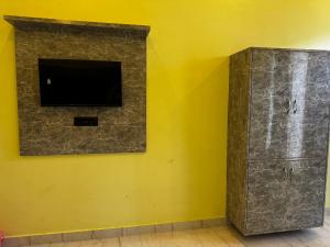 une télévision sur un mur jaune à côté d'une armoire dans l'établissement Akash home stay, à Mussoorie