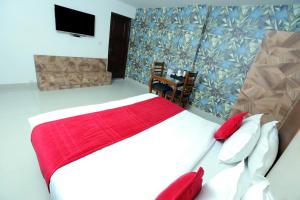 um quarto com uma cama grande e um cobertor vermelho em Hotel Mars Meg at Delhi Airport em Nova Deli