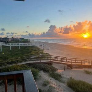 a sunset at the beach with a wooden fence at Surfside Beachfront Luxe in Surfside Beach