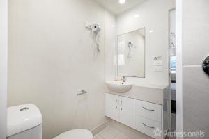 La salle de bains blanche est pourvue d'un lavabo et de toilettes. dans l'établissement Superior Studio 17 Endeavour, à Emu Park