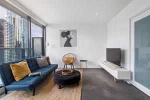 sala de estar con sofá azul y TV en Southbank Bella - New Listing, en Melbourne