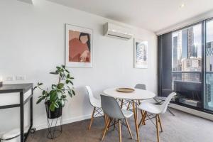 una sala de estar blanca con mesa y sillas en Southbank Bella - New Listing, en Melbourne