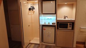 una pequeña cocina con nevera y microondas en ホテルシエル富士店 -大人専用-, en Fuji