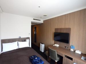 佐世保市にあるサンウエストホテル　佐世保のベッド、デスク、テレビが備わるホテルルームです。