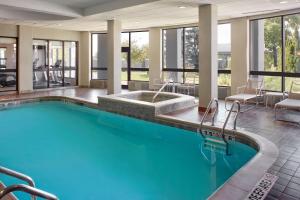 a large swimming pool in a hotel lobby with chairs and tables at Courtyard by Marriott Mississauga-Airport Corporate Centre West in Mississauga