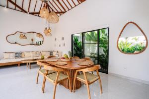 Un comedor con mesa y sillas de madera. en Villa Emilia, en Tanah Lot
