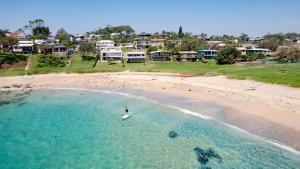 Malua BayMalua Bay Beachfront - Pet and EV Friendly的海滩上冲浪板上的人