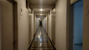 an empty hallway with a long corridor with black and white tiles at Hotel Avinash Inn Lodging in Nashik