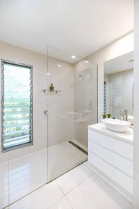ヌーサヘッズにあるSleek & Stylish Family Beach House ~ Near Junctionの洗面台とシャワー付きの白いバスルーム