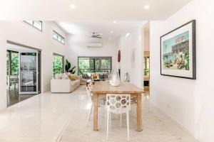 ヌーサヘッズにあるSleek & Stylish Family Beach House ~ Near Junctionのテーブルと椅子のあるキッチンとリビングルーム
