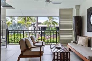een woonkamer met een bank en een balkon bij Devine Rooftop Penthouse at Temple Resort in Port Douglas