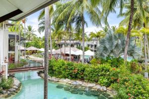 een uitzicht op een resort met een zwembad en palmbomen bij Devine Rooftop Penthouse at Temple Resort in Port Douglas