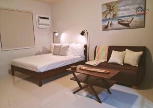 Cette chambre comprend un lit, un canapé et une table. dans l'établissement Palawan Cozy Studio with Balcony and Private Pool at T1 4Sapphire, à Puerto Princesa