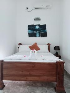 a bedroom with a large wooden bed with white sheets at Negombo Royal Villa by Oviniru in Negombo