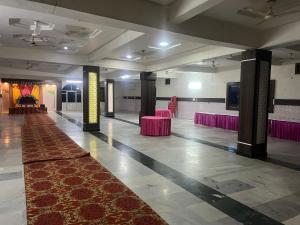a hall with pink chairs and a red carpet at Hotel JCM Chintpurni in Bharwain