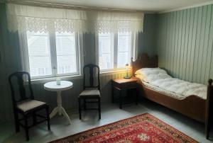 a bedroom with a bed and two chairs and a table at Kvammehuset på Gamle Lærdalsøyri in Lærdalsøyri