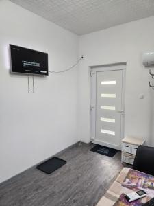 een kamer met een deur en een televisie aan de muur bij Nagyi Apartman Kecskemét in Kecskemét